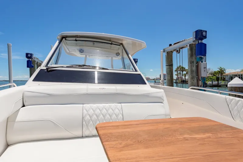  Yacht Photos Pics 2024 Regal 33 SAV boat interior with white seating and wooden table, docked under clear blue sky.