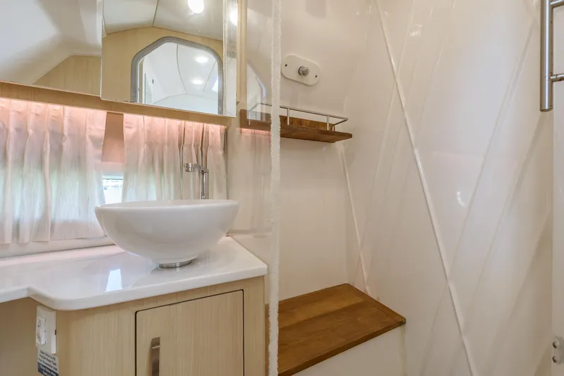  Yacht Photos Pics 2024 Regal 33 SAV bathroom with modern sink, wooden shelves, and elegant lighting.