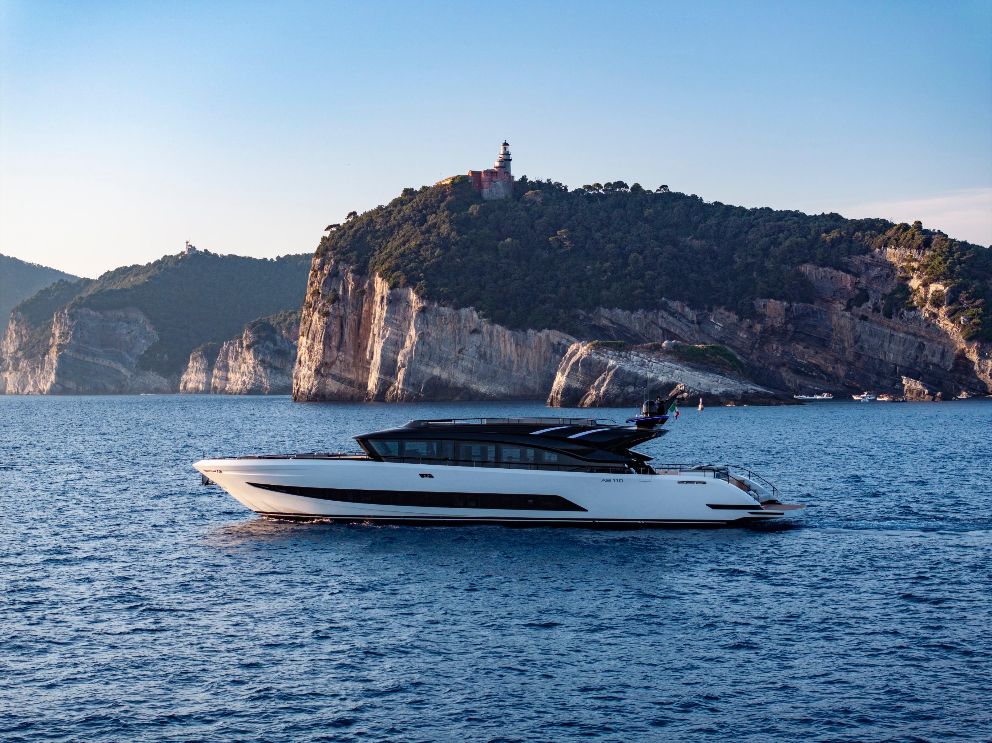 Luxurious 2026 AB 110 yacht cruising near scenic rocky coastline.