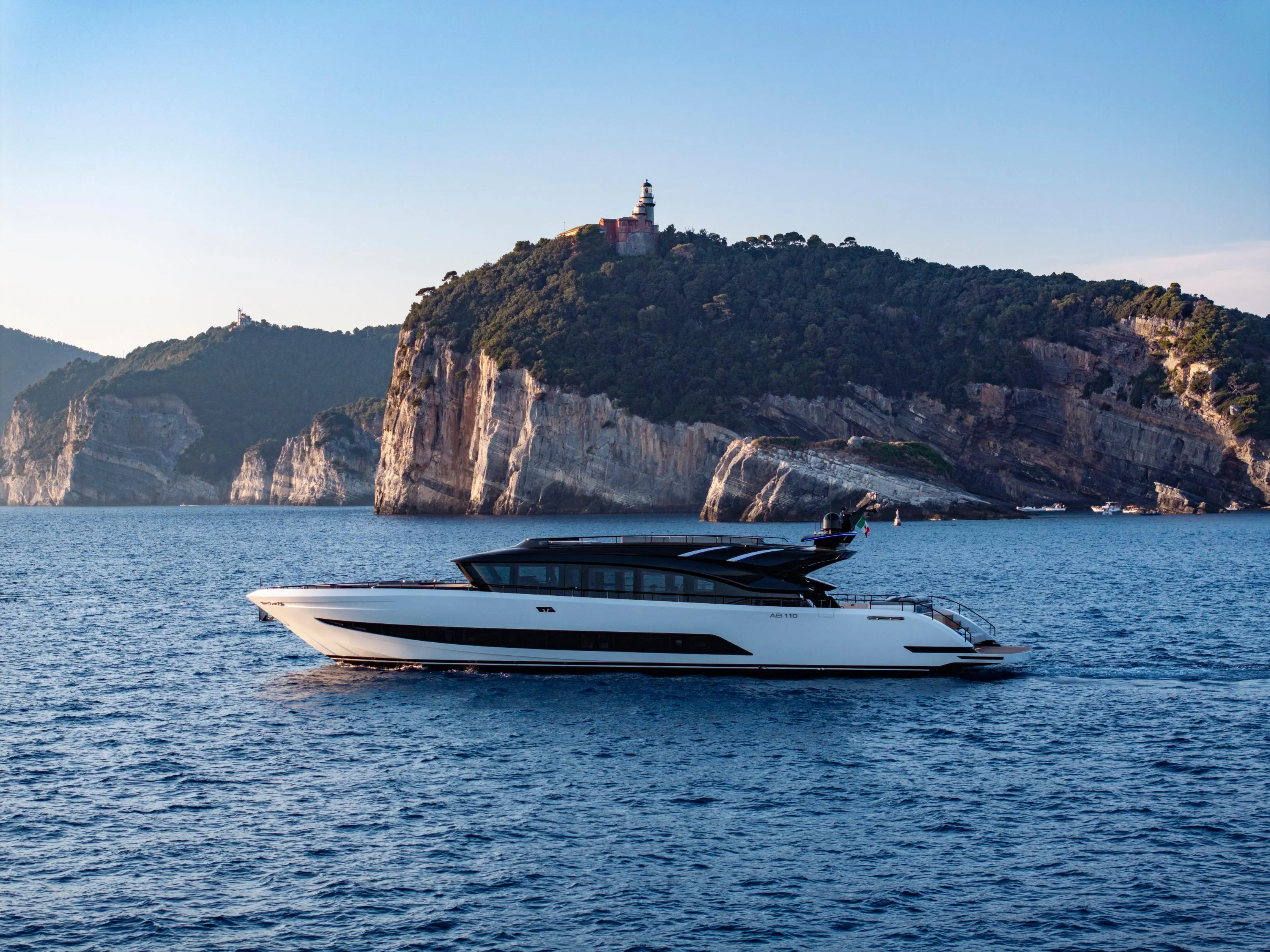 Luxurious 2026 AB 110 yacht cruising near scenic rocky coastline.