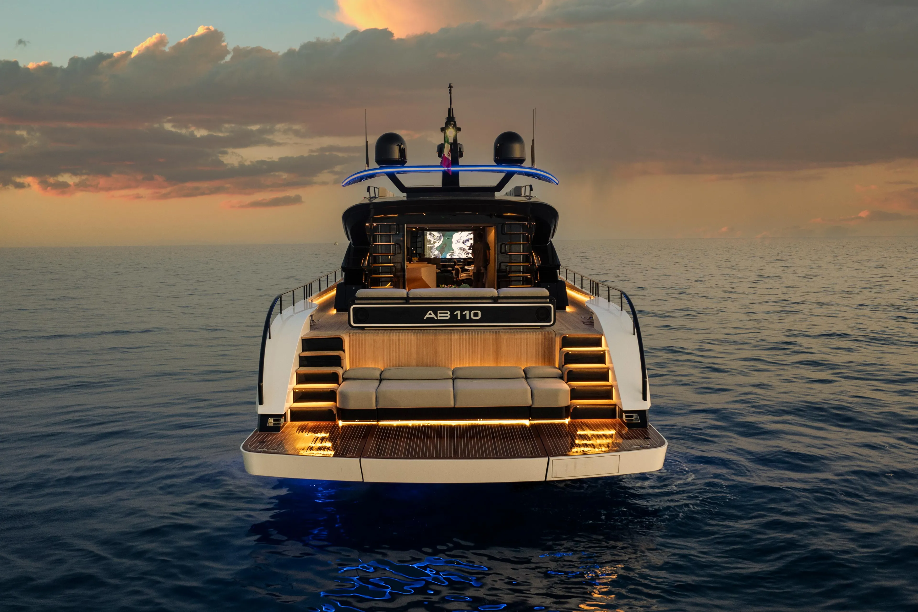 Luxury yacht AB 110, 2026 model, illuminated at sunset on open sea.