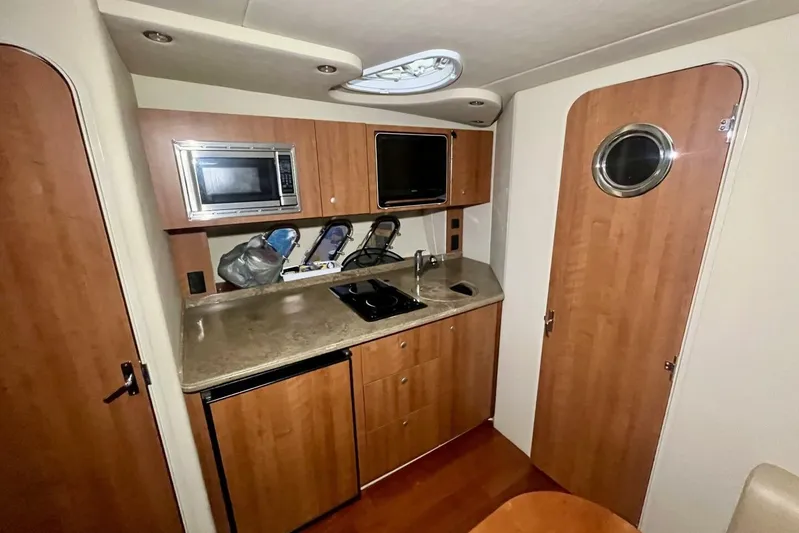  Yacht Photos Pics 2011 Cruisers Yachts 330 Express interior kitchen with microwave, sink, and wooden cabinetry.