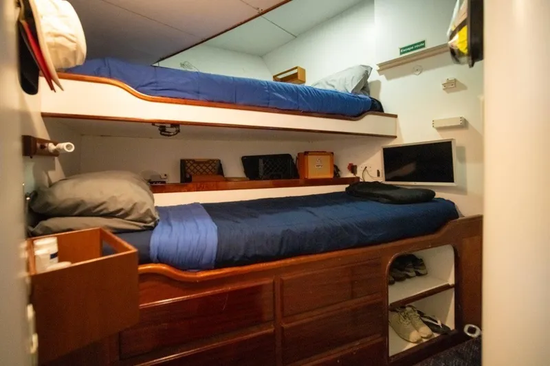 Flying Dutchman Yacht Photos Pics Cozy cabin with bunk beds on 1984 Lloyds Ships Tri-Deck yacht, featuring wooden storage and TV.