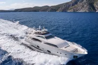 Luxurious 2007 Custom Line 97 yacht cruising on open sea near rocky coastline.