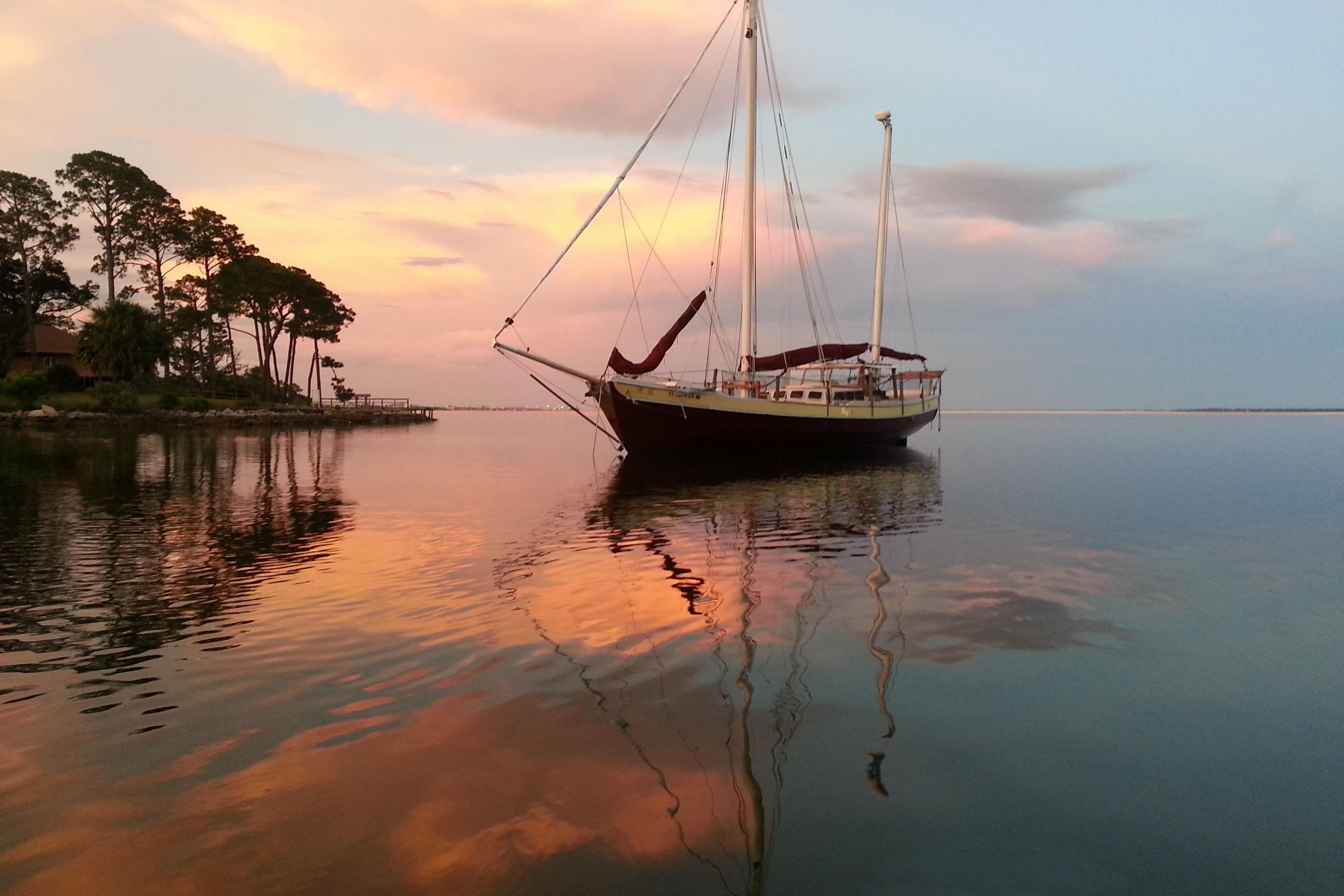 Sailboat "Lorcha 50" by Parker Marine, 2002, at sunset on calm waters.