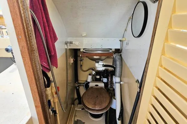 Tien Hou Yacht Photos Pics Compact marine bathroom in 2002 Parker Marine Lorcha 50 boat, featuring wooden toilet seat and sink.