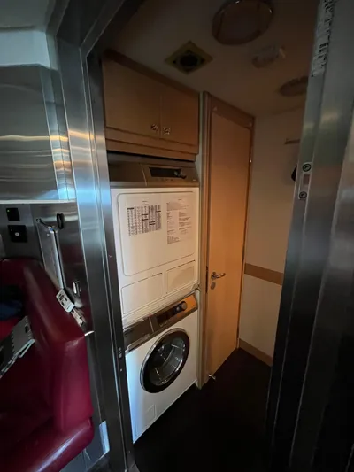 Izumi Yacht Photos Pics Laundry area inside a 2008 Palmer Johnson 120 yacht, featuring a stacked washer and dryer.