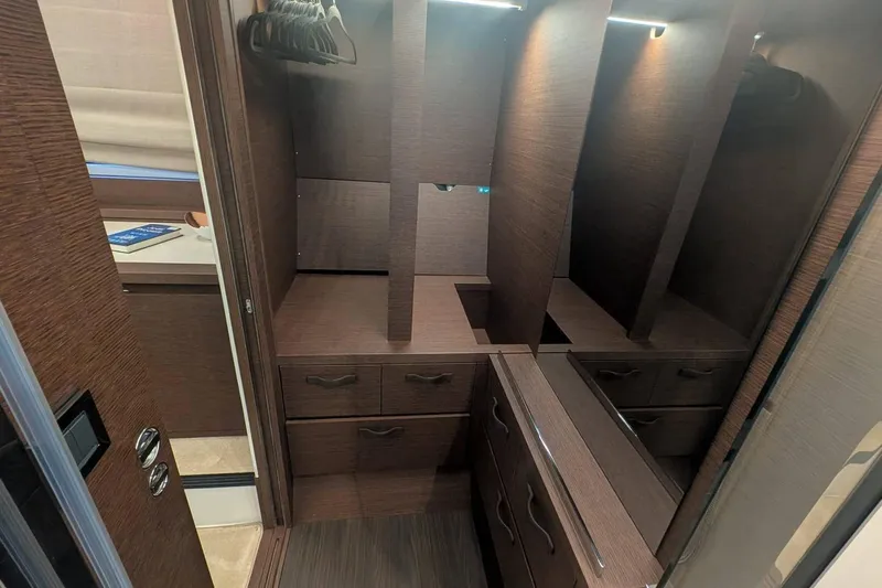  Yacht Photos Pics Luxurious wooden closet interior in 2022 Prestige 590 yacht, featuring drawers and hangers.
