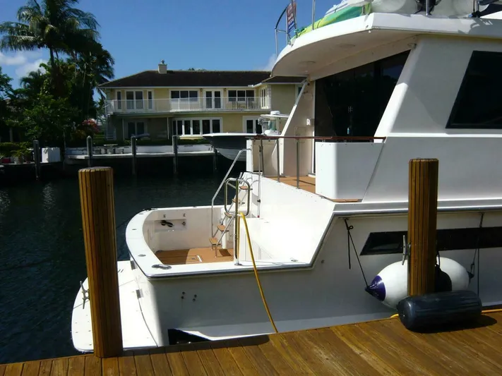 Vitamin Sea Yacht Photos Pics 1990 Viking Cockpit Motor Yacht docked near waterfront home, sunny day.