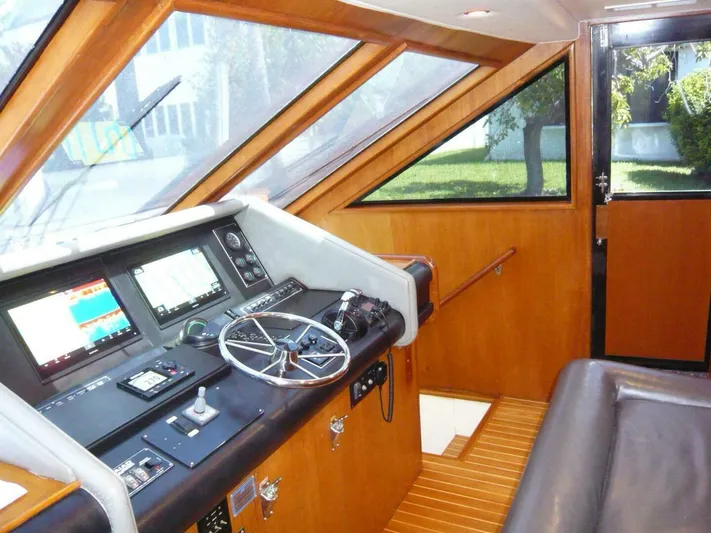 Vitamin Sea Yacht Photos Pics 1990 Viking Cockpit Motor Yacht interior with steering wheel, navigation screens, and wooden paneling.