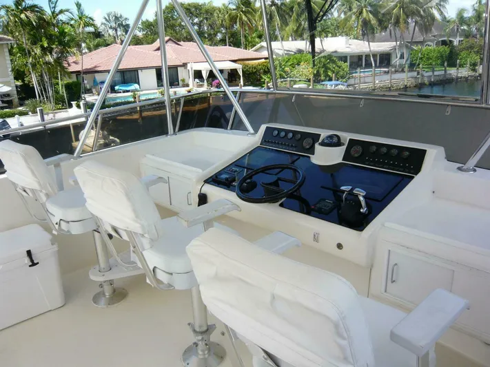 Vitamin Sea Yacht Photos Pics 1990 Viking Cockpit Motor Yacht helm with white seating and control panel, docked near waterfront homes.