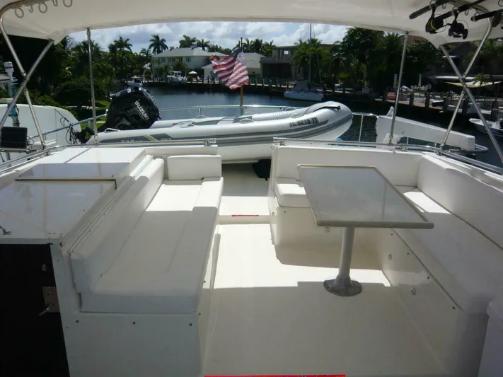 Vitamin Sea Yacht Photos Pics 1990 Viking Cockpit Motor Yacht with seating area and table, docked near a waterfront.