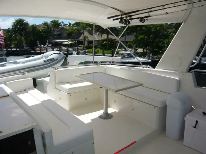 Vitamin Sea Yacht Photos Pics 1990 Viking Cockpit Motor Yacht with spacious outdoor seating and table, docked near lush greenery.