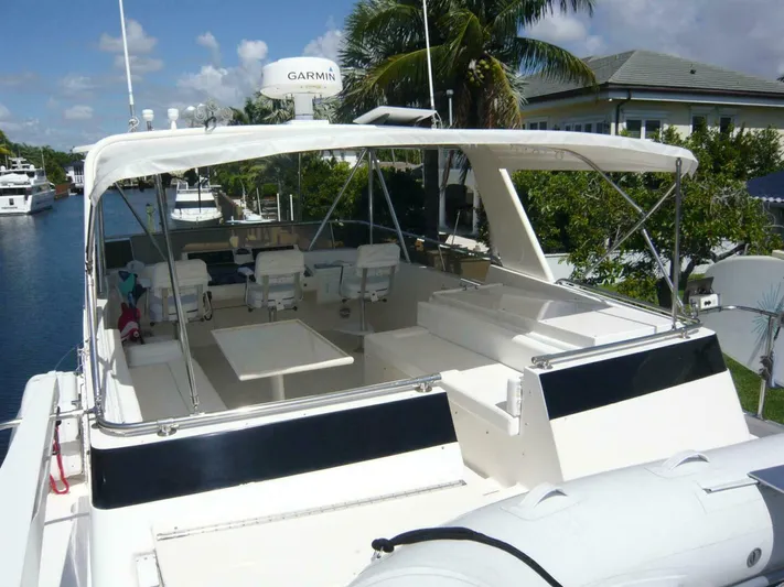 Vitamin Sea Yacht Photos Pics 1990 Viking Cockpit Motor Yacht with spacious seating and canopy, docked near lush greenery.