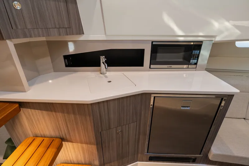  Yacht Photos Pics Modern kitchenette in 2023 Sea Ray 370 Sundancer yacht with sink, microwave, and fridge.