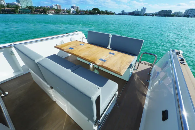  Yacht Photos Pics 2018 Fjord 36 Xpress boat with seating and table, overlooking turquoise water and cityscape.