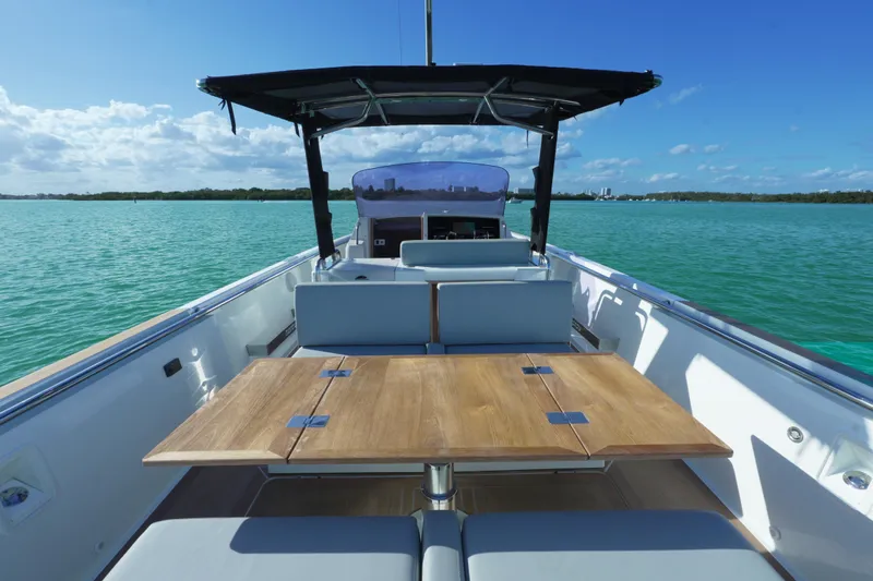  Yacht Photos Pics 2018 Fjord 36 Xpress boat with wooden table, cruising on turquoise waters under a clear blue sky.