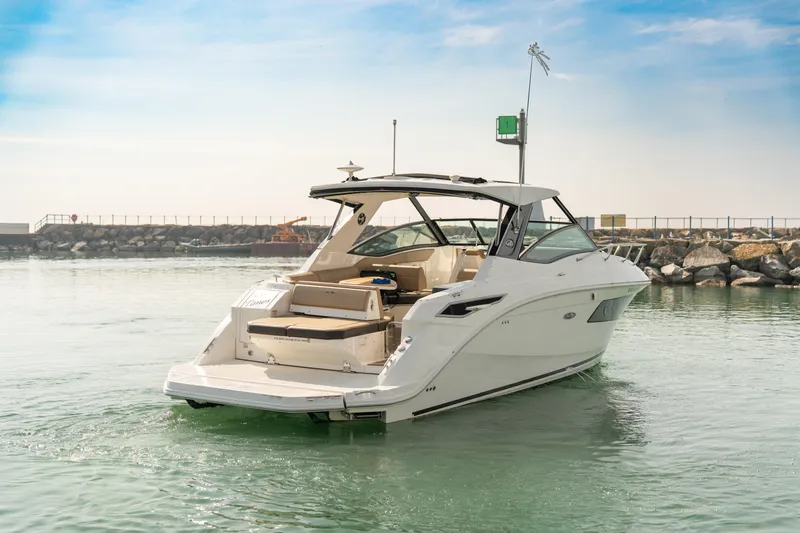 At Times Yacht Photos Pics 2019 Sea Ray Sundancer 320 yacht cruising in calm waters near a rocky shoreline.