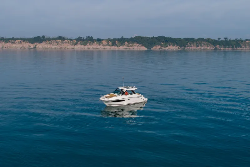 At Times Yacht Photos Pics 2019 Sea Ray Sundancer 320 cruising on calm blue waters near a scenic coastline.