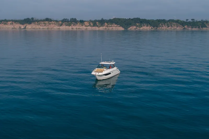 At Times Yacht Photos Pics 2019 Sea Ray Sundancer 320 yacht on calm blue water with scenic coastline backdrop.