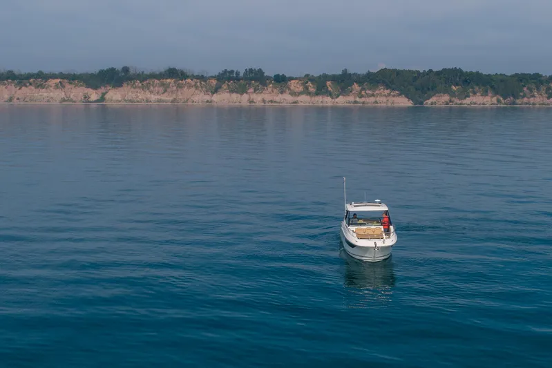 At Times Yacht Photos Pics 2019 Sea Ray Sundancer 320 cruising on calm waters near a scenic coastline.