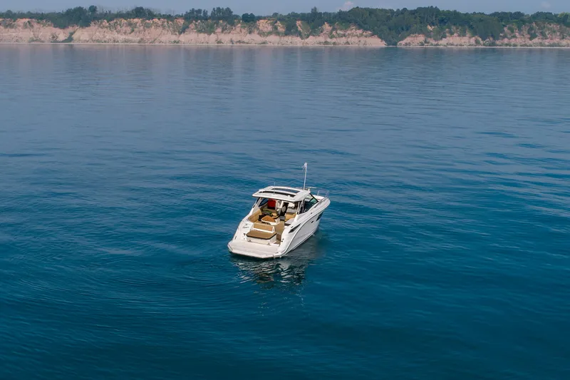 At Times Yacht Photos Pics 2019 Sea Ray Sundancer 320 yacht on calm blue water with scenic coastline.