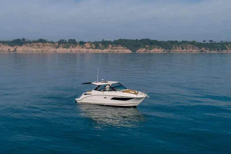 At Times Yacht Photos Pics 2019 Sea Ray Sundancer 320 cruising on calm waters near a scenic coastline.
