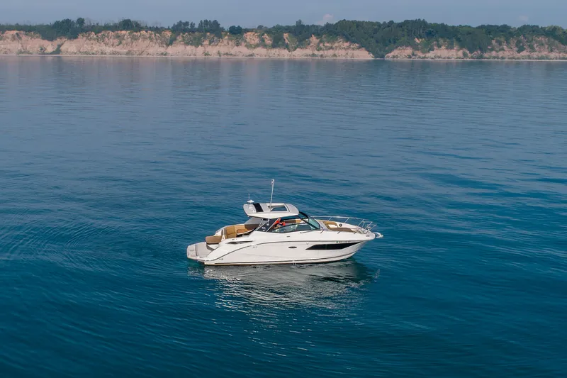 At Times Yacht Photos Pics 2019 Sea Ray Sundancer 320 cruising on calm blue waters near a scenic coastline.