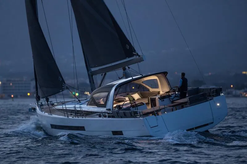  Yacht Photos Pics 2025 Jeanneau Yachts 55 sailing at dusk, illuminated interior, sleek design, cutting through waves.