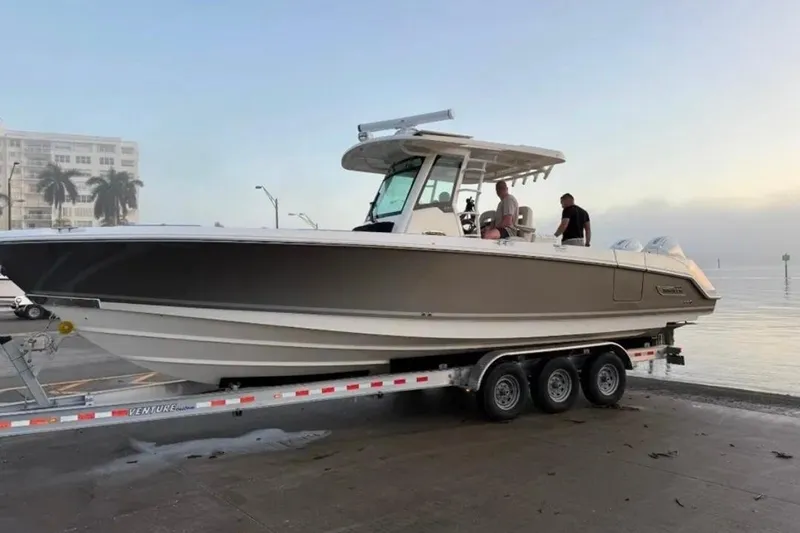 Timber Yacht Photos Pics 2023 Boston Whaler 330 Outrage on trailer by waterfront, with people onboard.