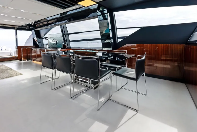 Our Trade Yacht Photos Pics Modern dining area on the 2021 Riva 88' FOLGORE yacht with sleek black chairs and large windows.
