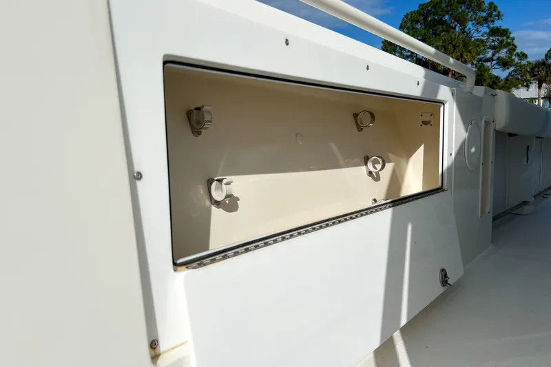  Yacht Photos Pics Edgewater 318CC 2011 boat storage compartment with open hatch, white interior, and sunny background.