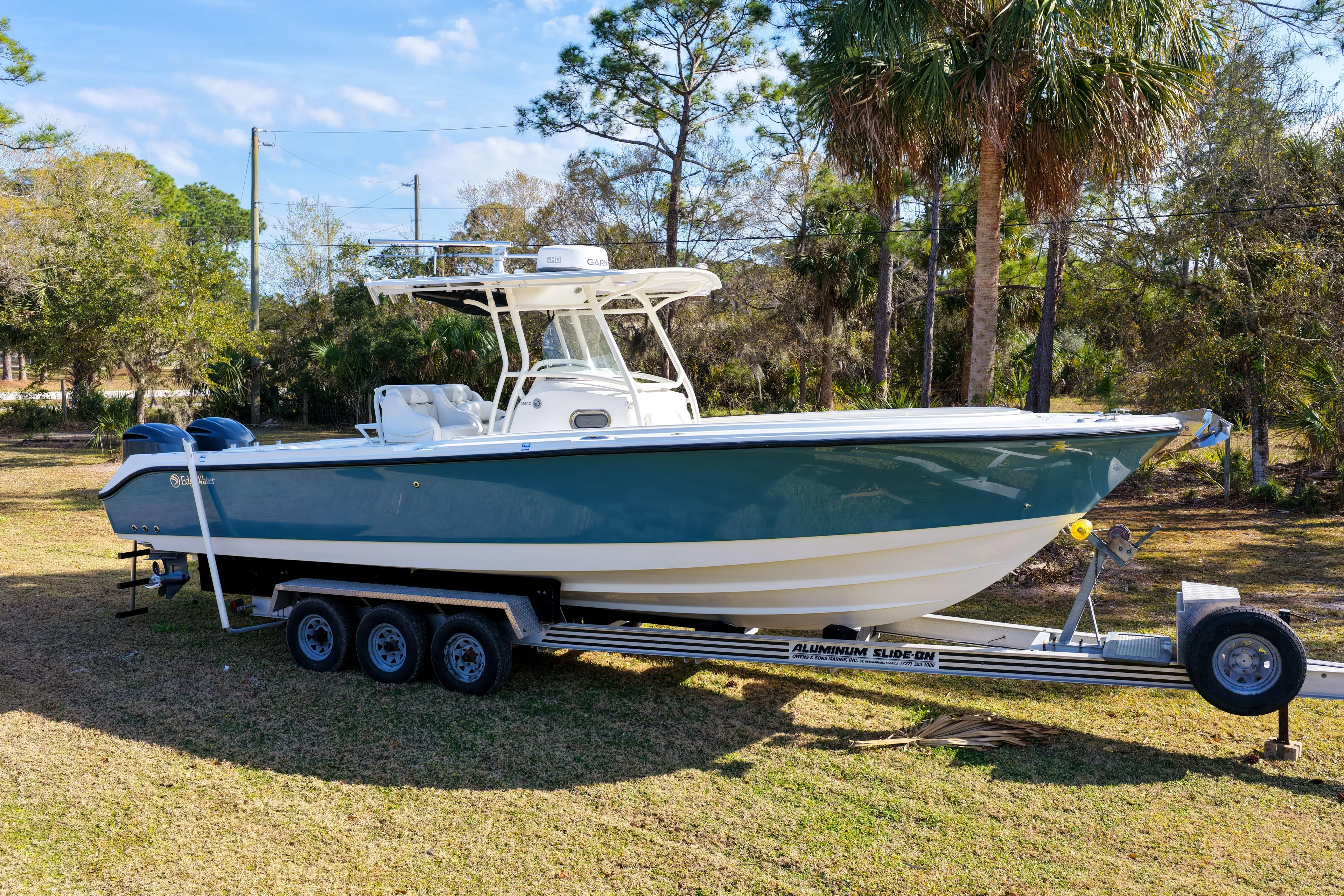  Yacht Photos Pics 2011 Edgewater 318CC boat on trailer, parked on grass with trees in background.