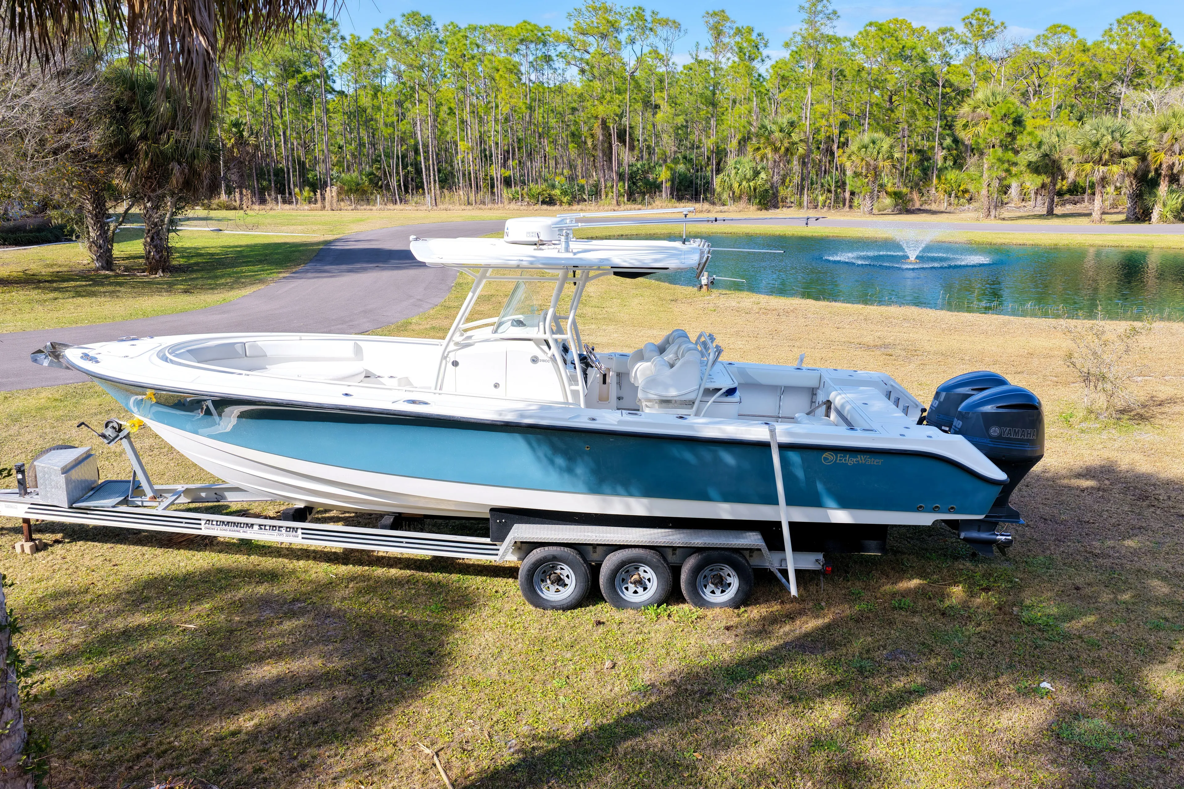  Yacht Photos Pics 2011 Edgewater 318CC boat on trailer by a pond, surrounded by trees.