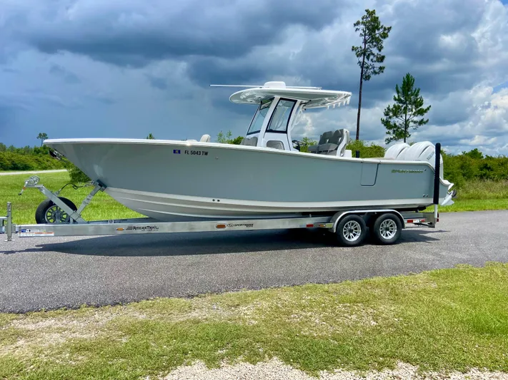  Yacht Photos Pics 2025 Sportsman Open 262 Center Console boat on trailer, parked on road under cloudy sky.