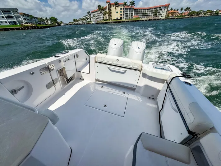 Yacht Photos Pics 2025 Edgewater 262 CX boat cruising on a sunny day with waterfront buildings in the background.