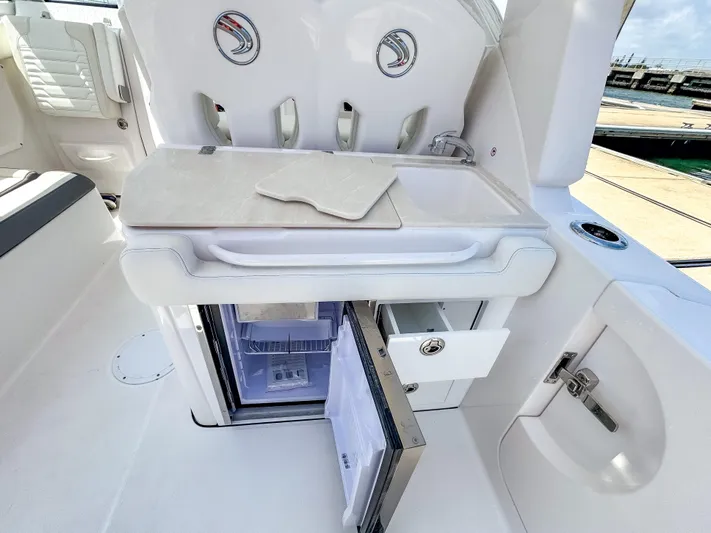  Yacht Photos Pics 2025 Edgewater 262 CX boat interior with open mini fridge and storage compartments.
