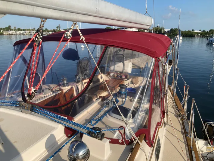 Andante Yacht Photos Pics 1995 Island Packet 37 sailboat with red canopy, docked on calm water.