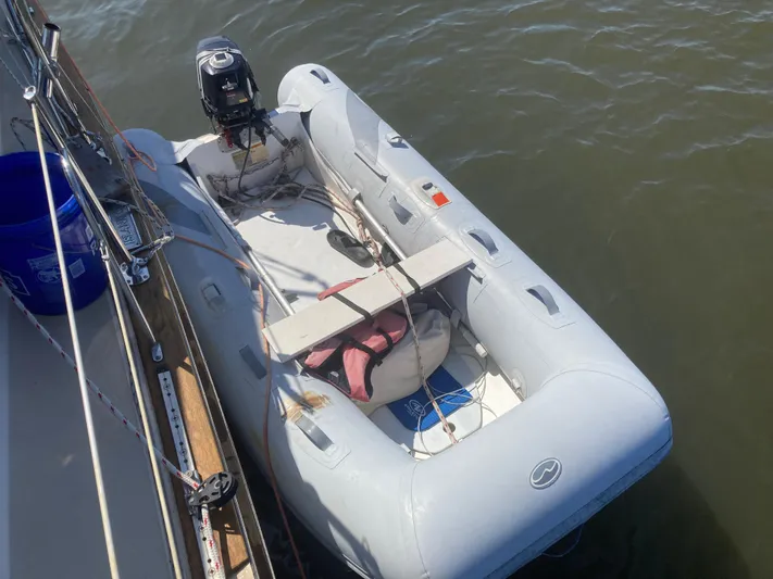 Andante Yacht Photos Pics Inflatable dinghy tied to a 1995 Island Packet 37 sailboat on calm water.
