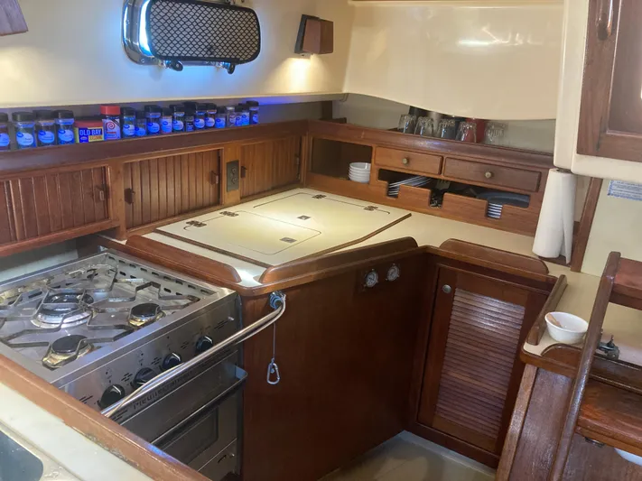 Andante Yacht Photos Pics 1995 Island Packet 37 yacht kitchen with stove, storage, and wooden cabinetry.