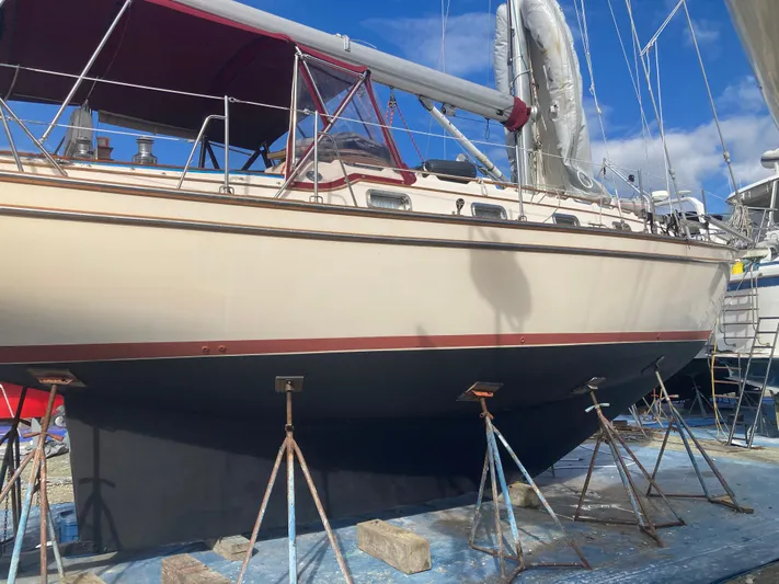Andante Yacht Photos Pics 1995 Island Packet 37 sailboat on stands, with a blue tarp underneath, under a clear sky.