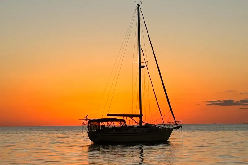 Andante Yacht Photos Pics Sailboat Island Packet 37, 1995 model, silhouetted against a vibrant sunset over calm waters.