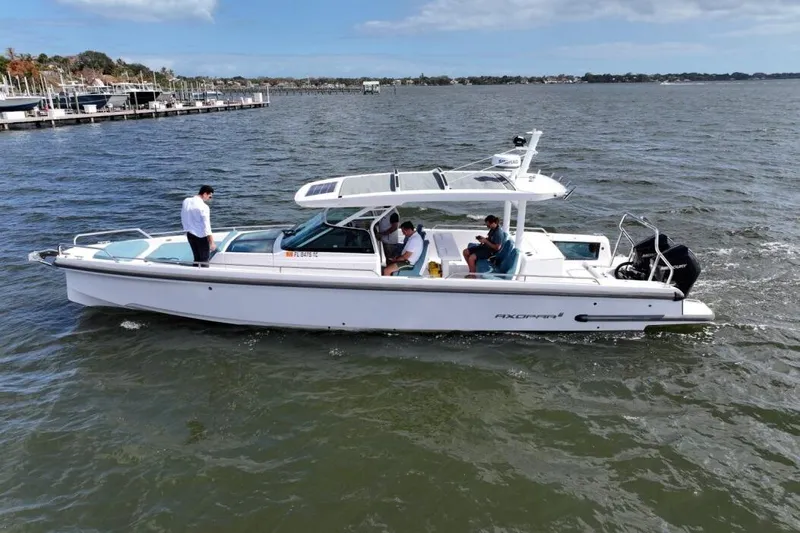  Yacht Photos Pics 2022 Axopar 37 Sun-Top boat cruising on a calm lake with passengers onboard.