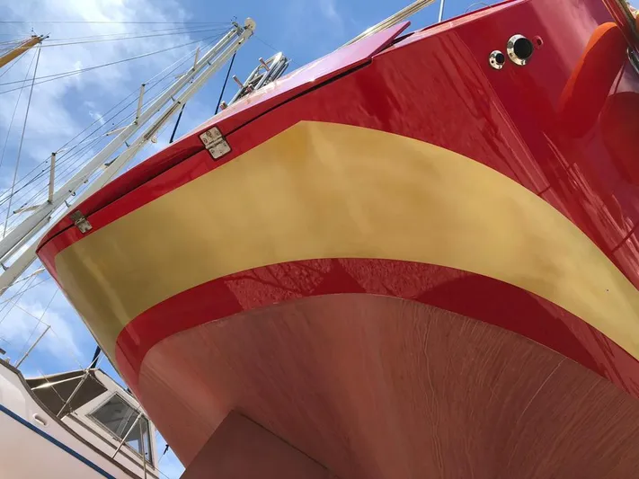 Felitsata II Yacht Photos Pics Red and yellow hull of 2011 Hanse 62 DS sailboat under blue sky.