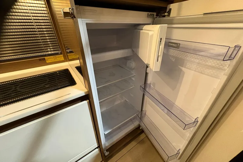  Yacht Photos Pics Open fridge inside 2022 Jeanneau Leader 46 yacht, showcasing spacious interior and shelving.