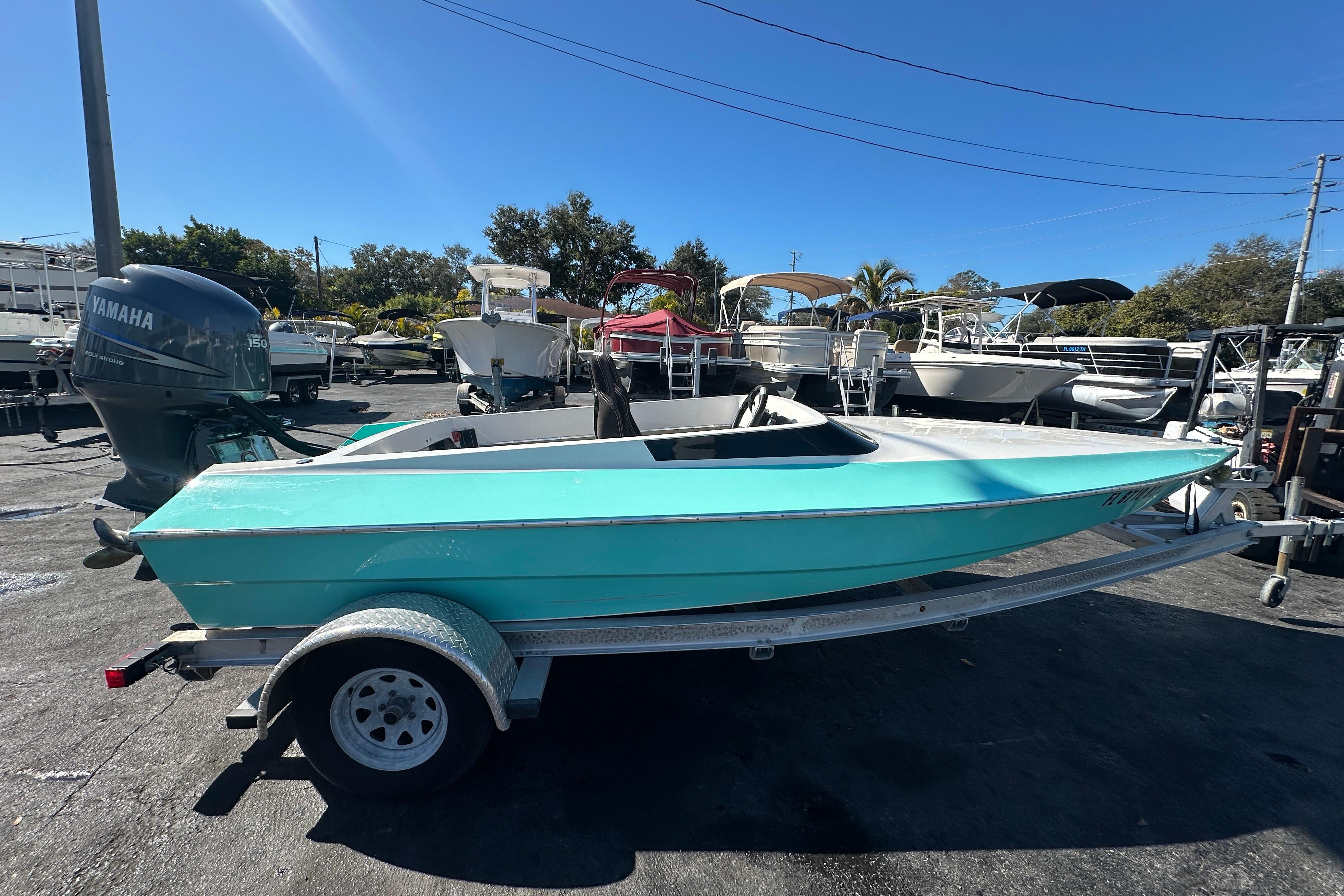 Turquoise 2022 Lightning 18 boat on trailer, parked in marina with Yamaha outboard motor.