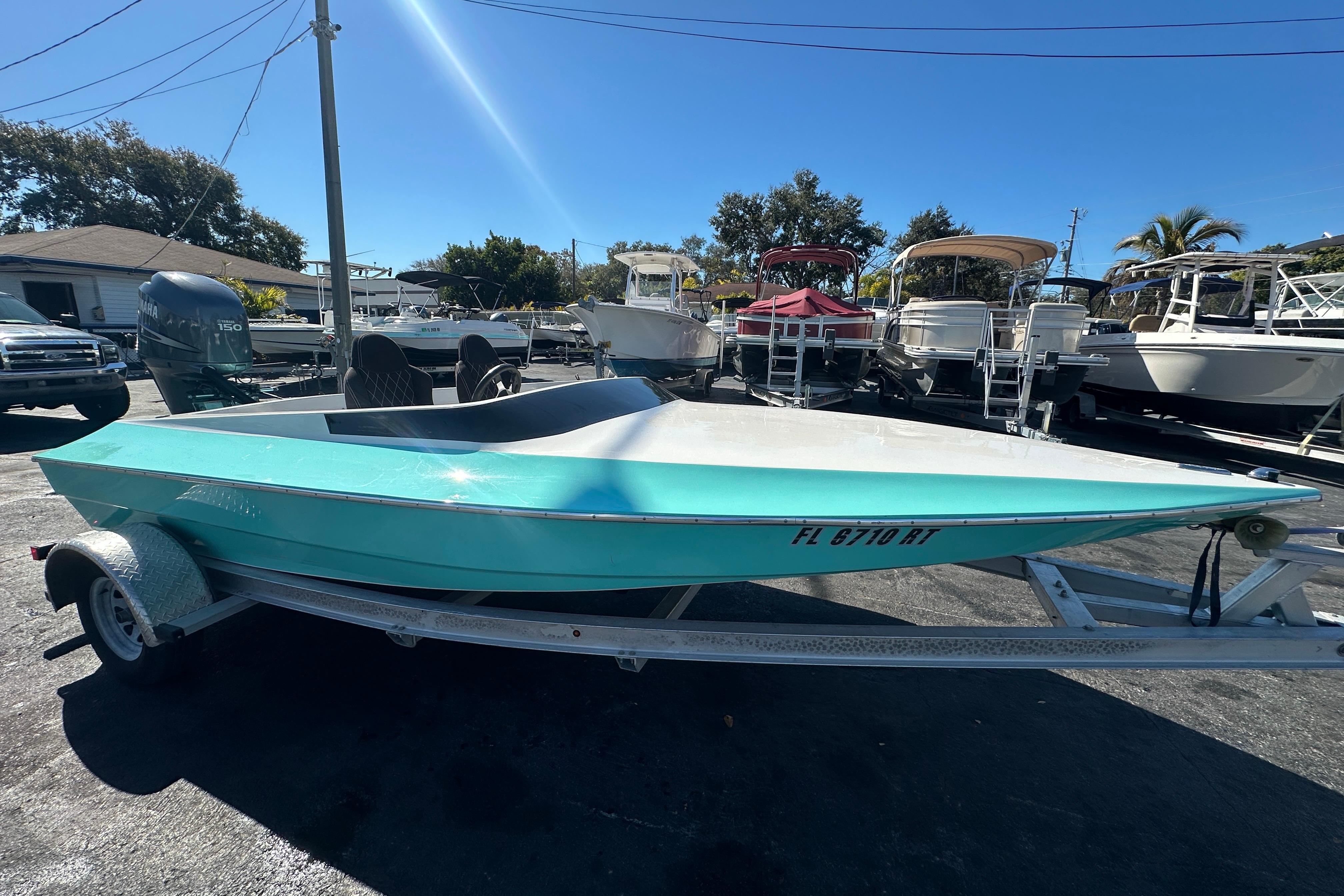 2022 Lightning 18 boat in turquoise on trailer, parked in marina under clear blue sky.