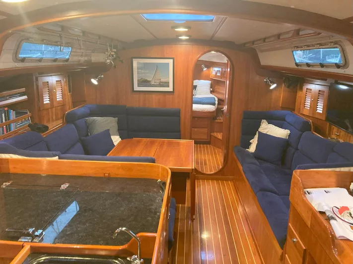 Harmony Yacht Photos Pics Luxurious 2005 Tillotson-Pearson J-160 yacht interior with wooden finishes and blue seating.