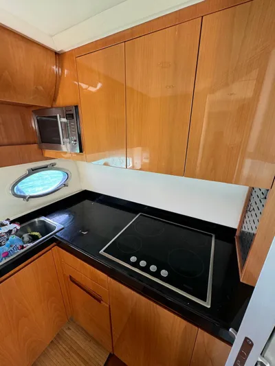  Yacht Photos Pics 2006 Pershing 56 yacht kitchen with wooden cabinets, black countertop, and built-in stove.