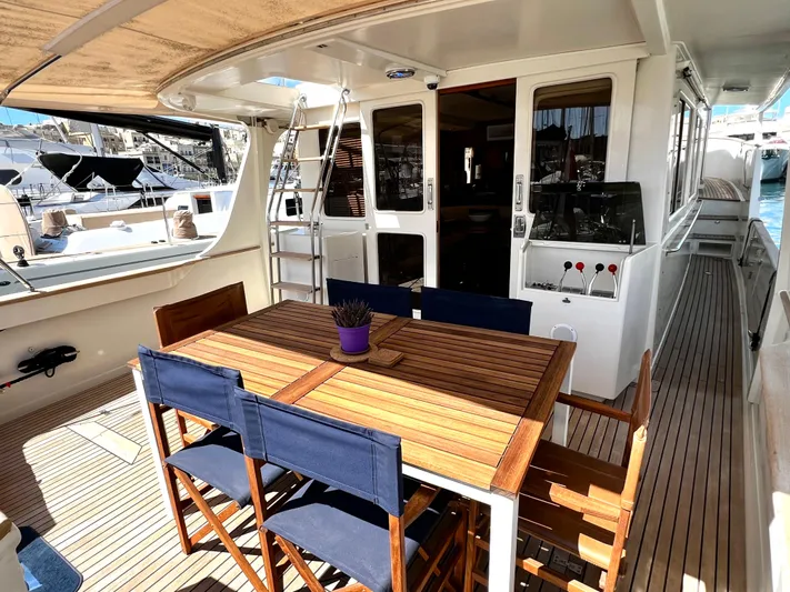  Yacht Photos Pics Outdoor dining area on a 1996 Fleming 55 yacht with wooden table and blue chairs.